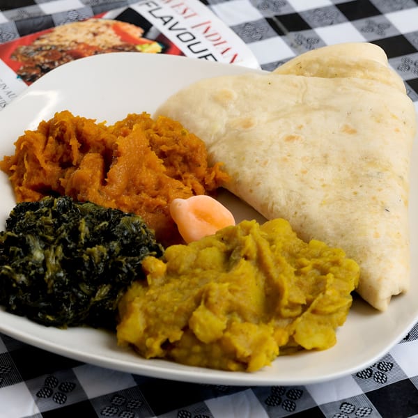 A Caribbean meal with flatbread, mashed pumpkin, stewed greens, and yellow split peas.